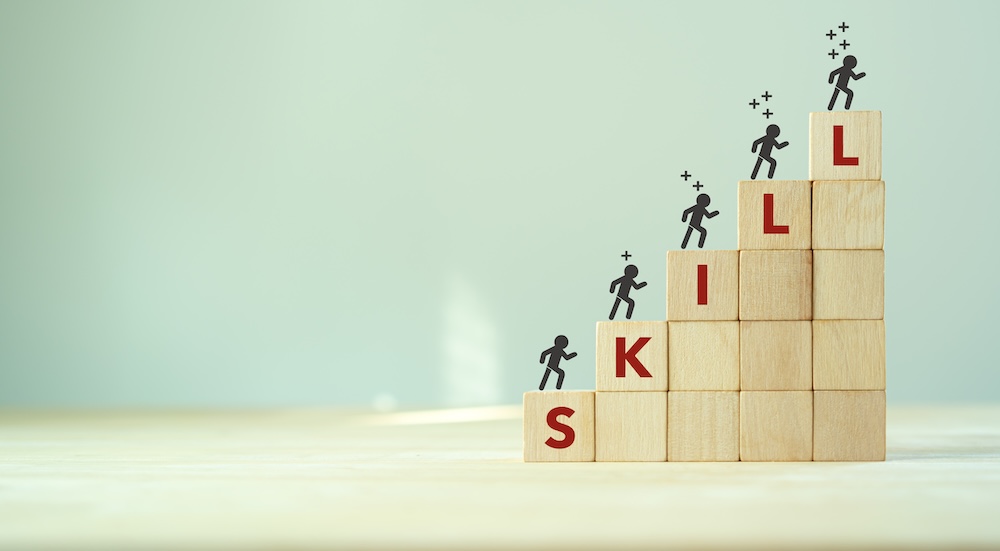 skillと英語で書かれた積み木を小人が登っているイメージ